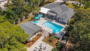 Luftaufnahme eines Wohnhauses mit Swimmingpool, Terrassenmöbeln und einer überdachten Außenbereich.
