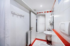 Ein modernes Badezimmer mit einem weißen Waschbecken, einem roten Fliesenboden und einer sichtbaren Duschkabine.