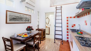 A compact kitchen with a dining area, a ladder, and a framed artwork on the wall. - Ardenza's Aires 600m From Sea (Livorno)
