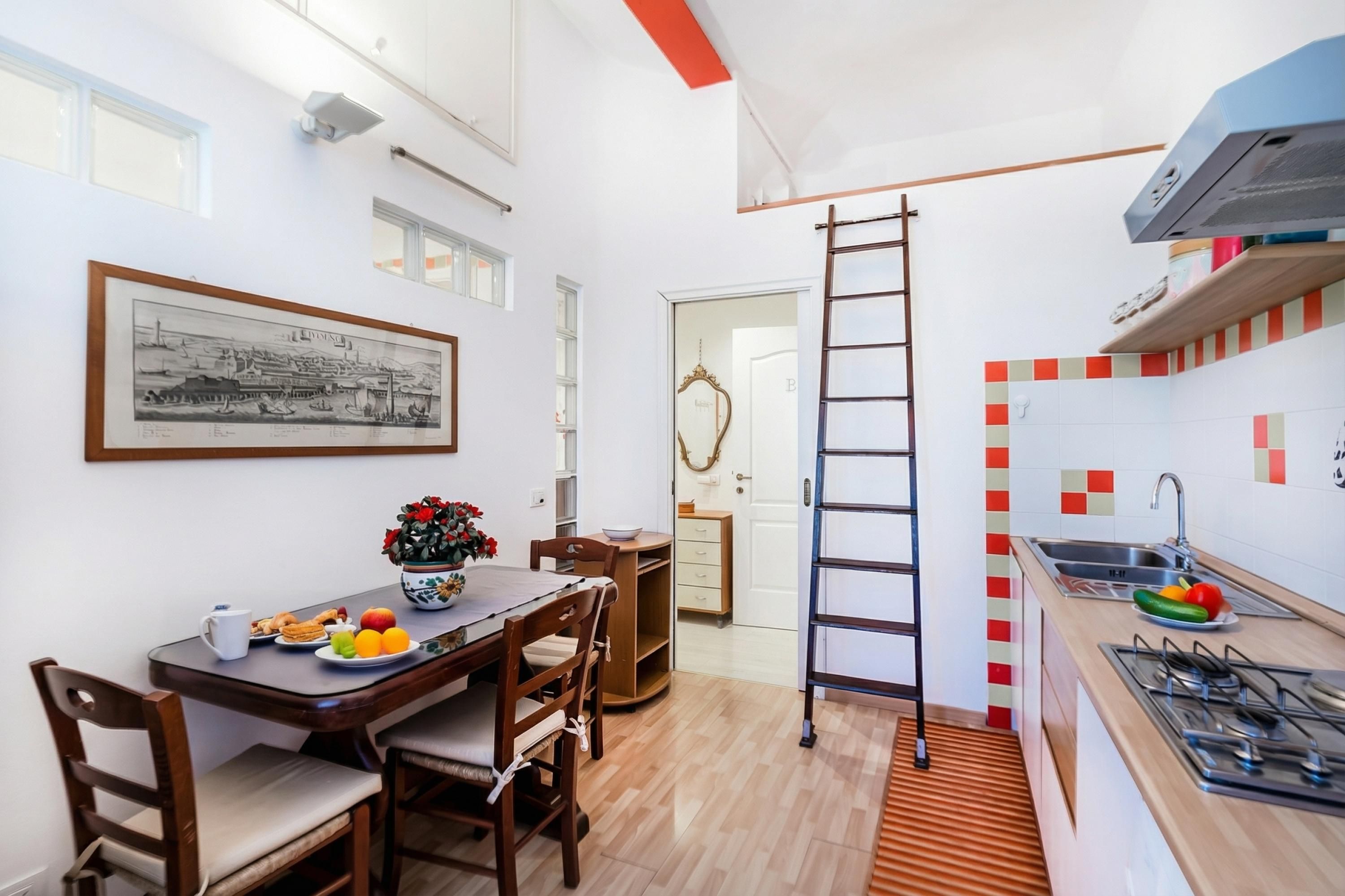 Una cocina compacta con comedor, una escalera y un cuadro en la pared.