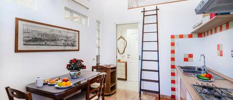 Una cocina compacta con comedor, una escalera y un cuadro en la pared.