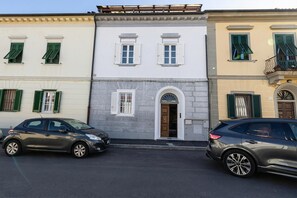 A row of three-story buildings with a central door and windows, parked cars, and a clear sky. - Ardenza's Aires 600m From Sea (Livorno)