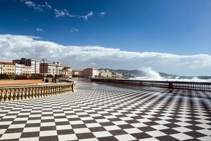 Ein Schachbrettmuster-Promenade mit Blick auf das Meer und Gebäude im Hintergrund.