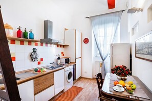 Eine kompakte Küche mit Waschmaschine, Mikrowelle und einem Essbereich mit gedecktem Tisch für das Frühstück.
