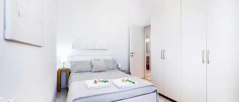 Un dormitorio con cama, mesita de noche, armario y una obra de arte colgada en la pared.