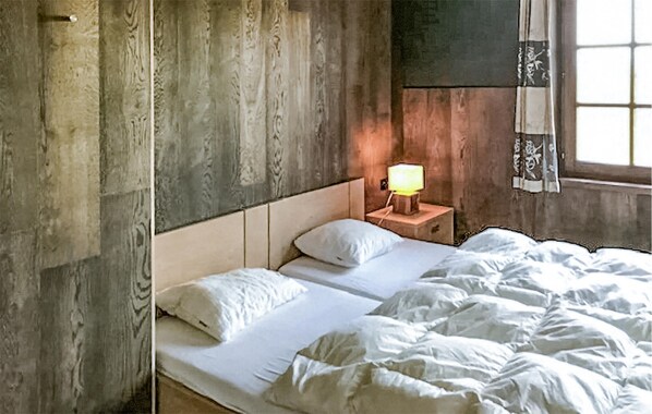 A bedroom with a wooden headboard, a bedside table with a lamp, and a window with curtains. - Pet friendly home in Durbuy with Wi-Fi (Durbuy)