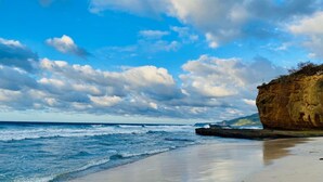 Una playa con olas, una orilla arenosa y un acantilado rocoso.
