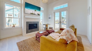A spacious living room with a fireplace, large windows, and a cozy seating area. - Resort Pools, Pet Friendly, Golf Cart Boardwalk to Beach (Port Aransas)