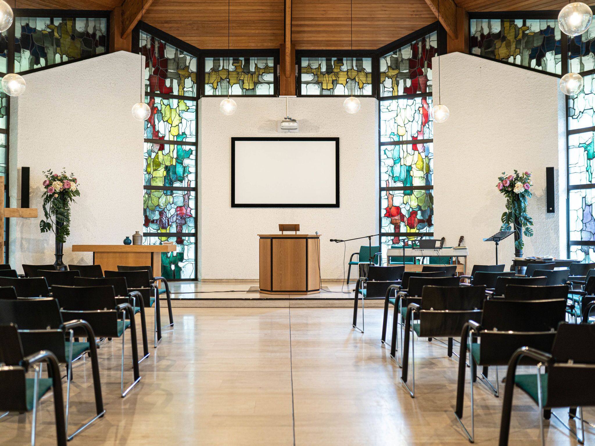 A church interior with pews, a wooden podium, and stained glass windows.