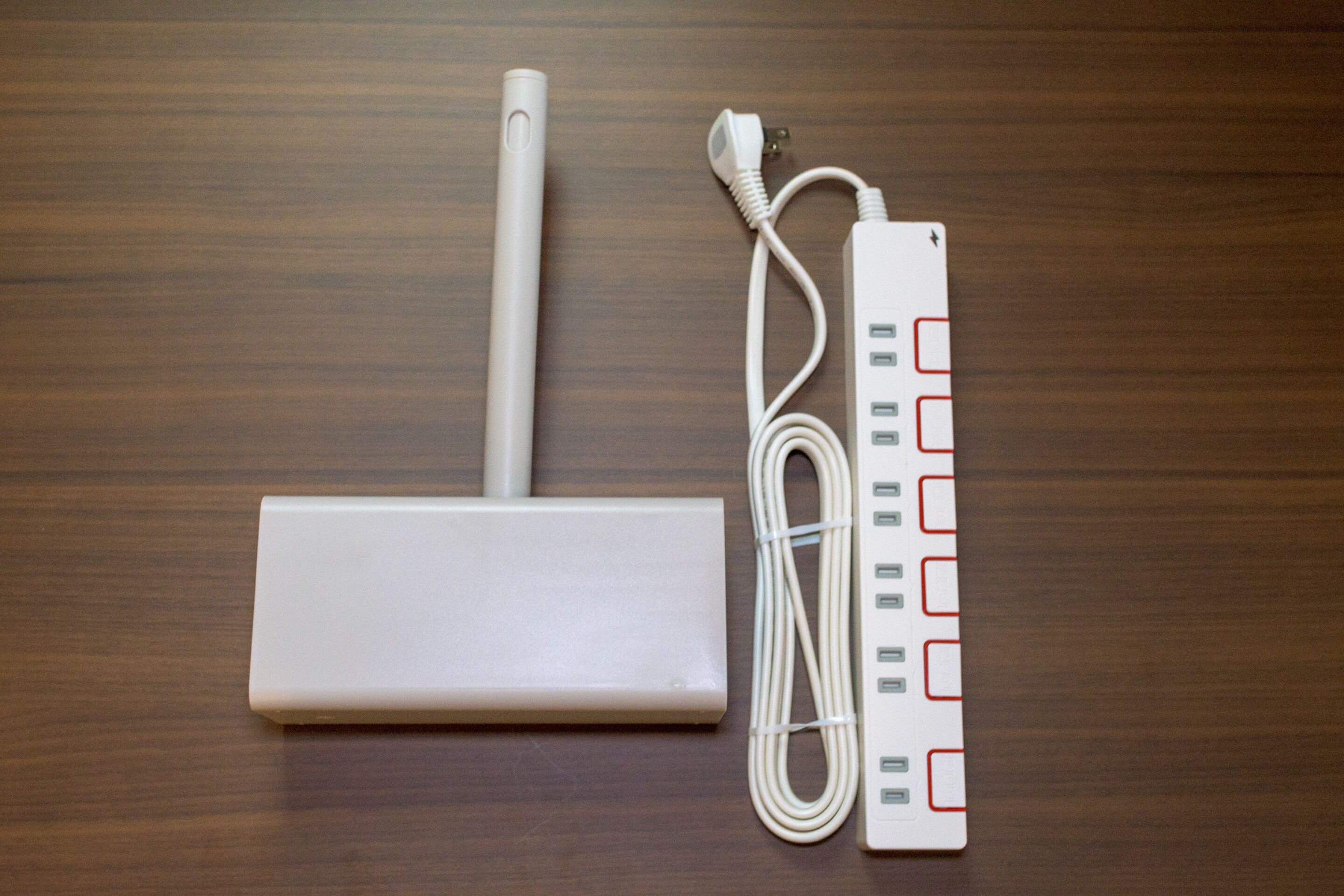 A white power strip with multiple USB ports and a coiled cable on a wooden surface.