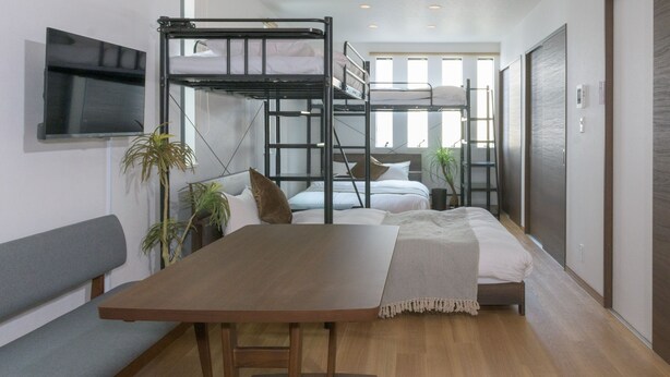 Une chambre moderne et compacte, dotée de lits superposés, d’une table à manger en bois et d’un téléviseur fixé au mur.
