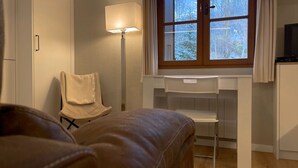 Une chambre à coucher comprenant un lit, une chaise, un bureau et une fenêtre donnant sur des arbres.