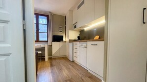 Une cuisine de taille réduite avec des meubles blancs, un four à micro-ondes et un petit plan de travail.
