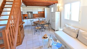 A spacious living area with a wooden staircase, a dining table with chairs, a sofa, and a glass coffee table. - Le Green Village by Interhome (Roquebrune sur Argens)