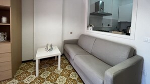 Una zona d'estar petita i ben ordenada, amb un sofà, una taula petita i un armari.