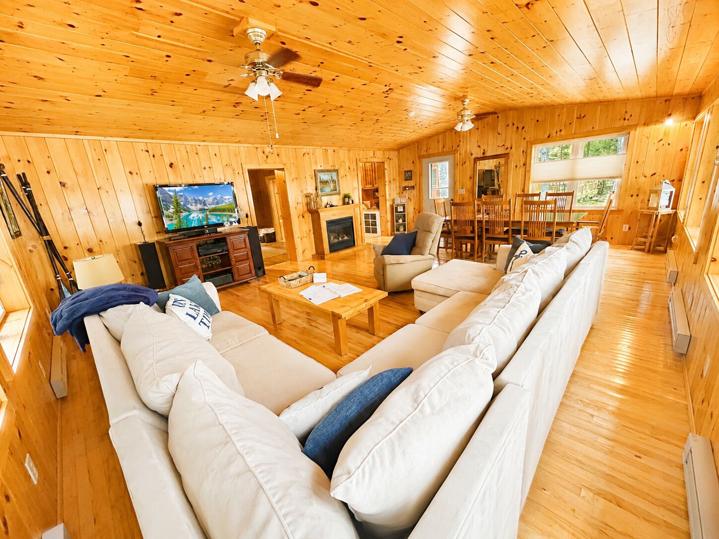 A wooden interior with a sofa, television, and a fireplace.