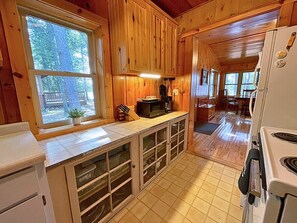 A wooden cabin kitchen with a large window, a microwave, and a refrigerator. - Ford's Talpine Cottage on Echo Lake (Mercer)