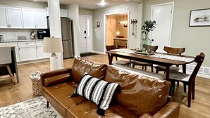 A modern living room with a brown leather sofa, a dining table with chairs, a kitchen area, and a ceiling fan. - Fort Smith / Furnished 4 BR / Nurses, Ebbing, TDY (Fort Smith)