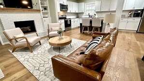 A modern living room with a leather sofa, a round coffee table, and a fireplace. - Fort Smith / Furnished 4 BR / Nurses, Ebbing, TDY (Fort Smith)