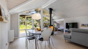 En rummelig opholdsstue med spisebord, stole, sofa og fjernsyn.