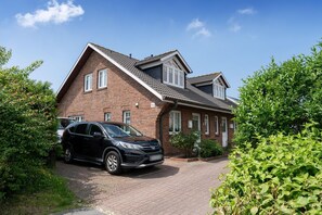 Een tweelaags bakstenen huis met een auto op de oprit.
