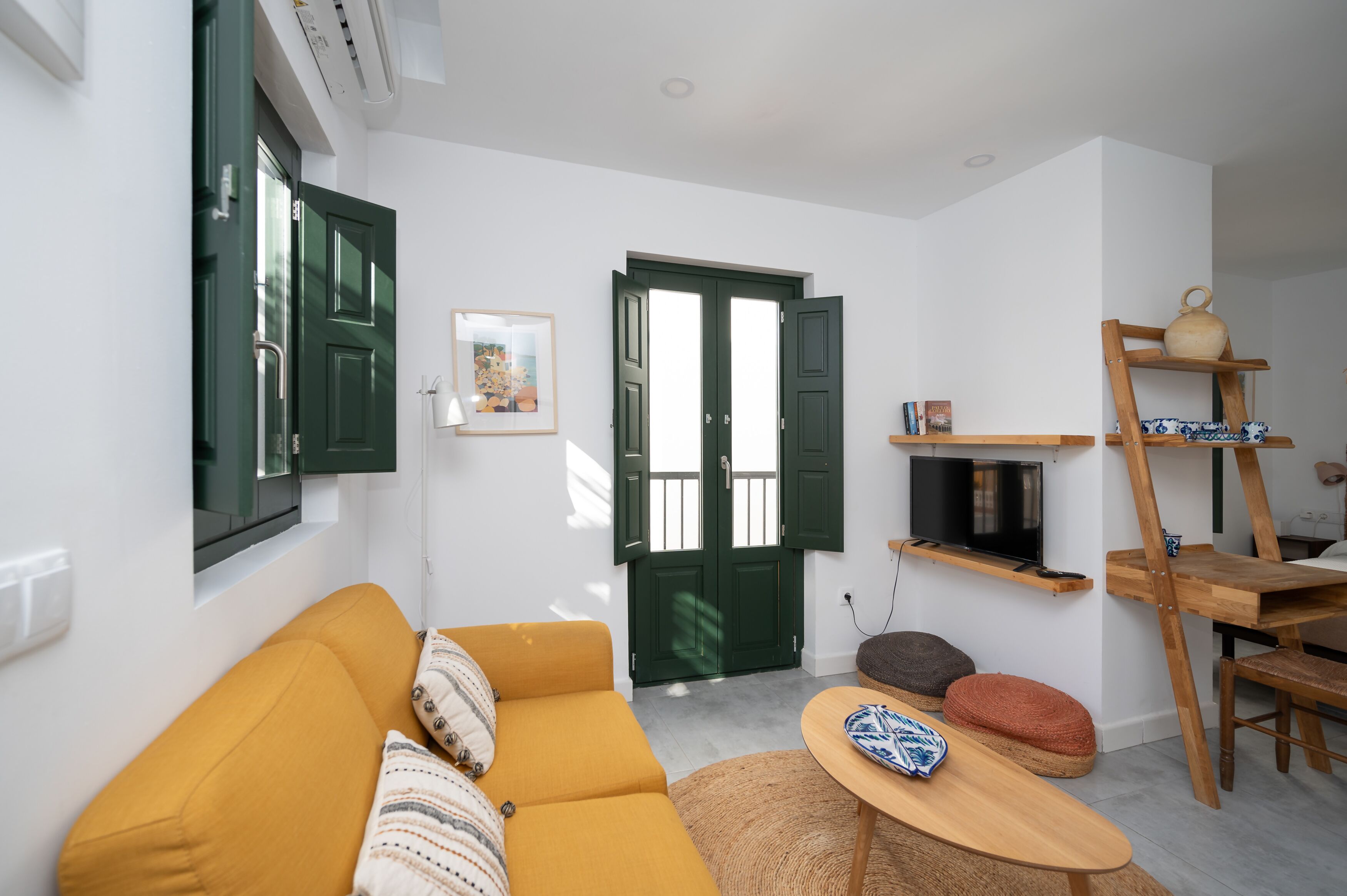 Un salón moderno con un sofá amarillo, una mesa de madera y una puerta verde.