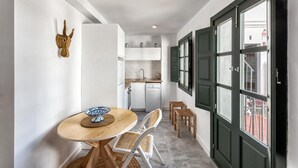 A compact kitchen with white cabinets, a sink, and a window with green shutters. - Lovely studio in peaceful courtyard (Arroyo De La Miel)