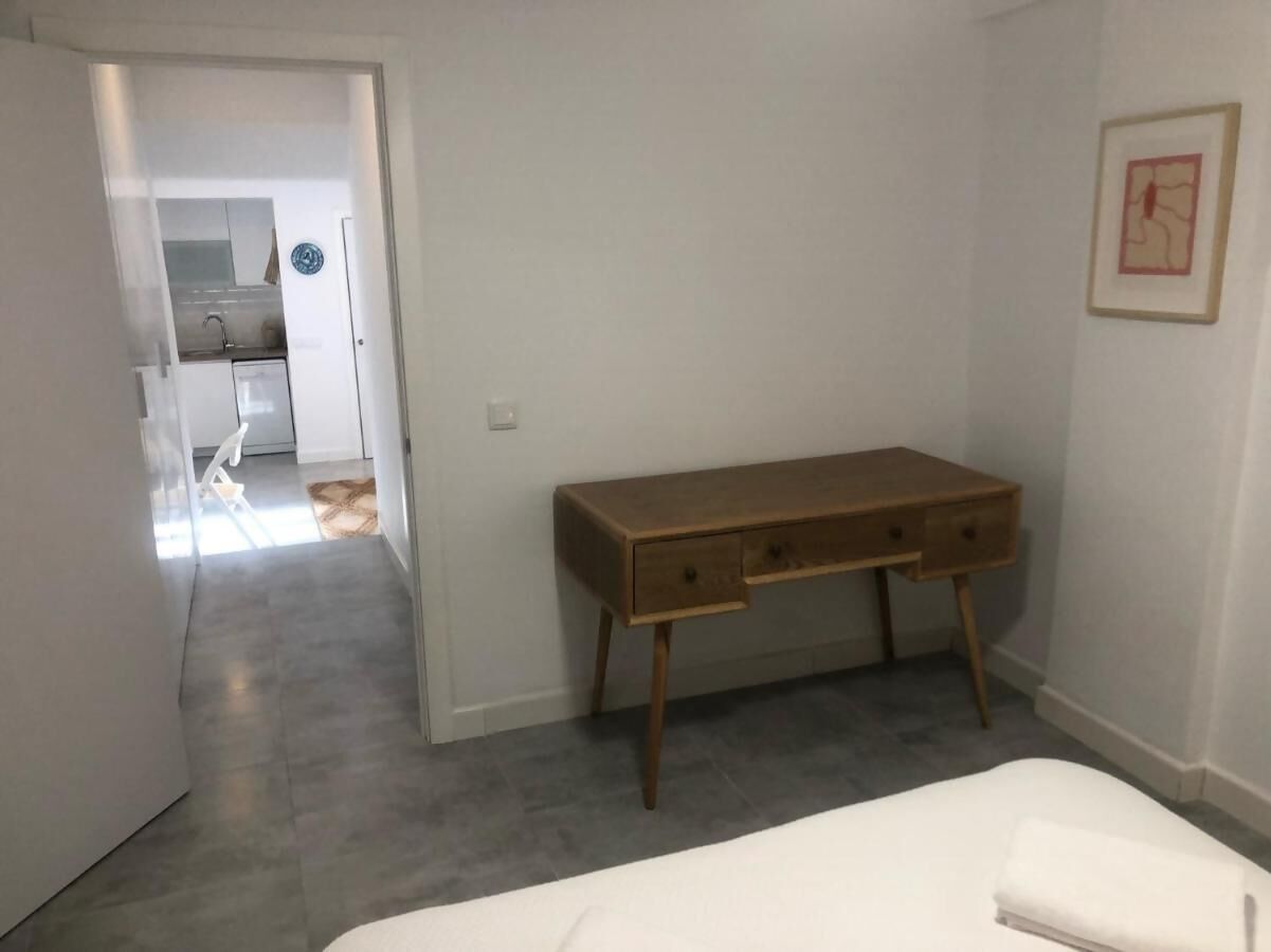 Un dormitorio con una cama, un escritorio de madera y una puerta que da al baño.