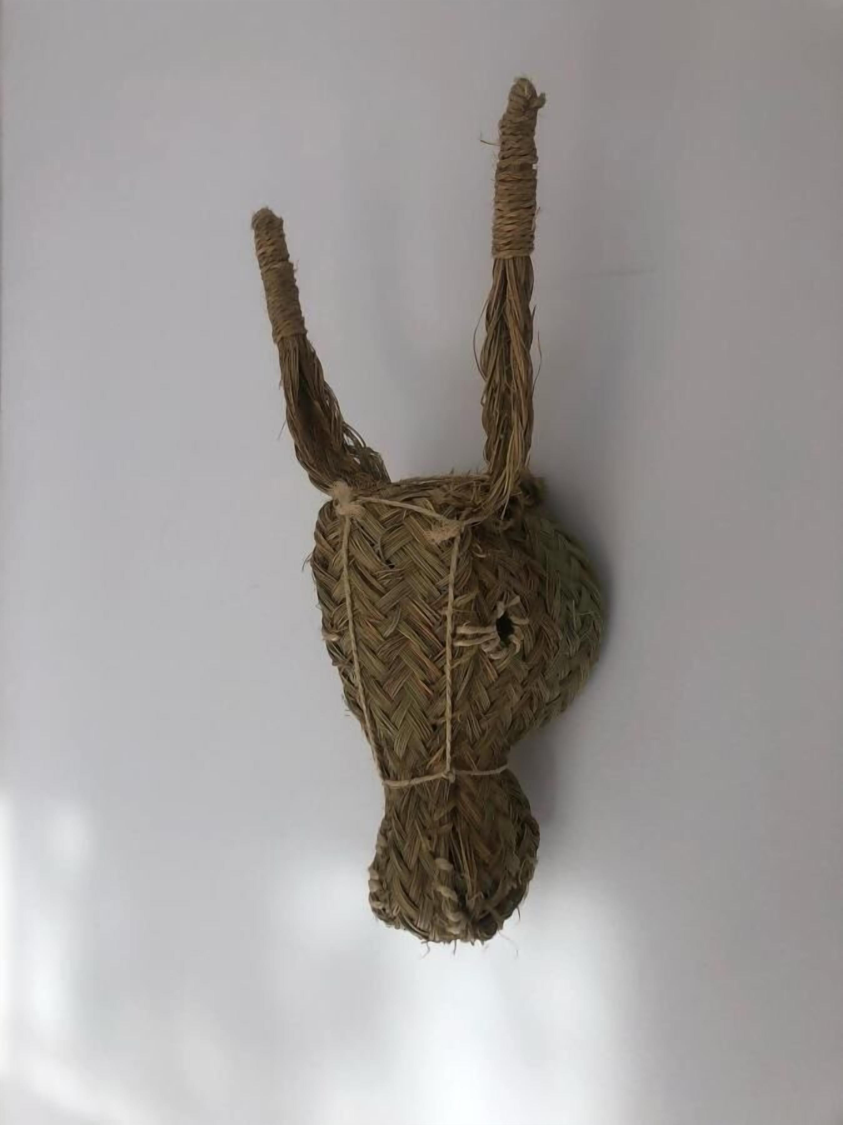 A woven wall hanging in the shape of a rabbit's head.