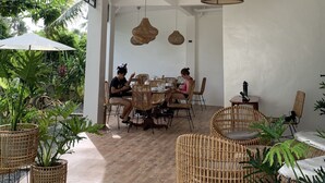 An indoor dining area with wicker furniture, a white ceiling, and hanging wicker lamps. - Bahandi Hotel (General Luna)