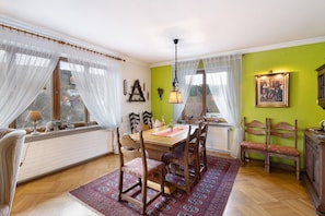 Un comedor con una mesa, sillas, una lámpara colgante y vistas a través de una ventana.