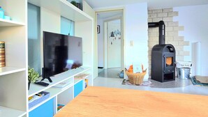 Una sala de estar con televisor, mesa de madera y chimenea.
