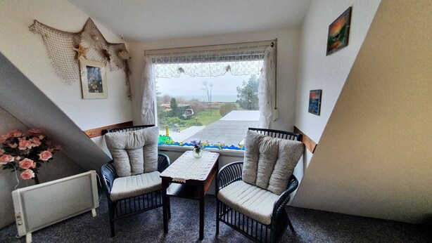Una habitación con vista al mar, dos sillas, una mesita y un radiador.