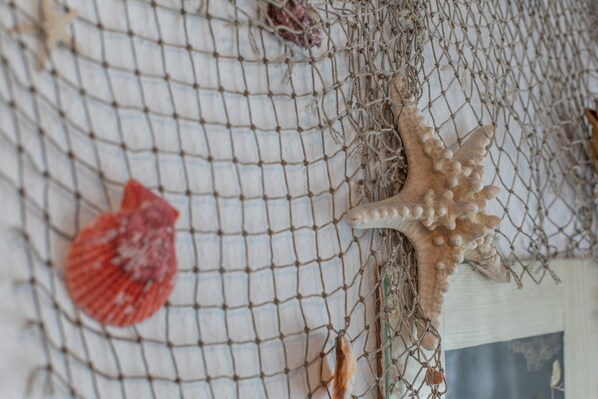 Primer plano de una red con una estrella de mar y una concha marina adheridas.