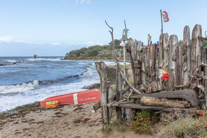 Una playa con una valla de madera, un flotador salvavidas y una bandera.