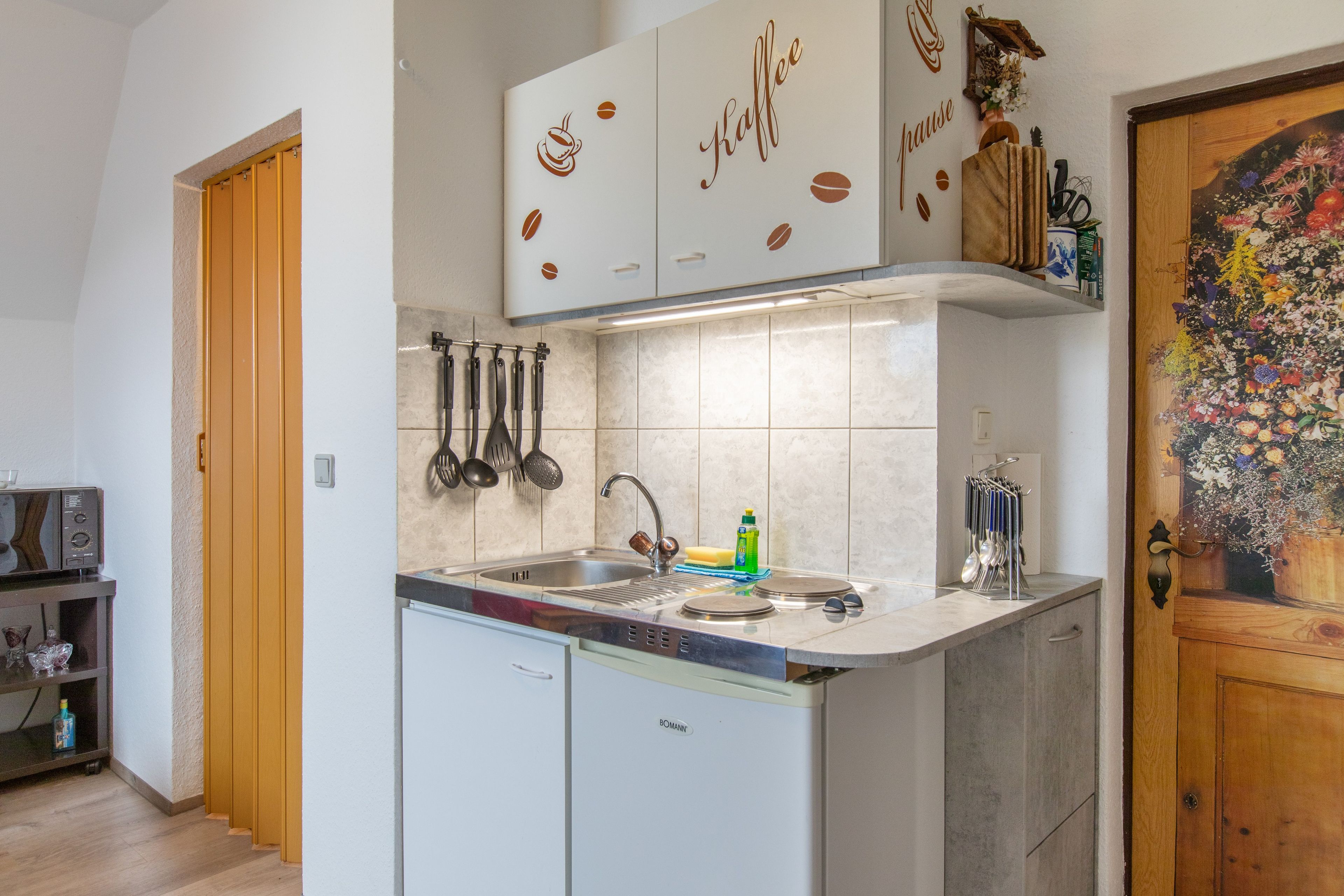 Una cucina con lavastoviglie integrata, macchina del caffè e lavello con rubinetto moderno.