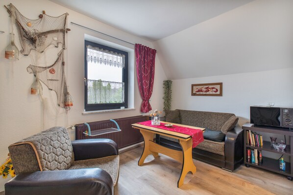 Una sala de estar con una mesa de madera, un sofá, un televisor y una estantería.