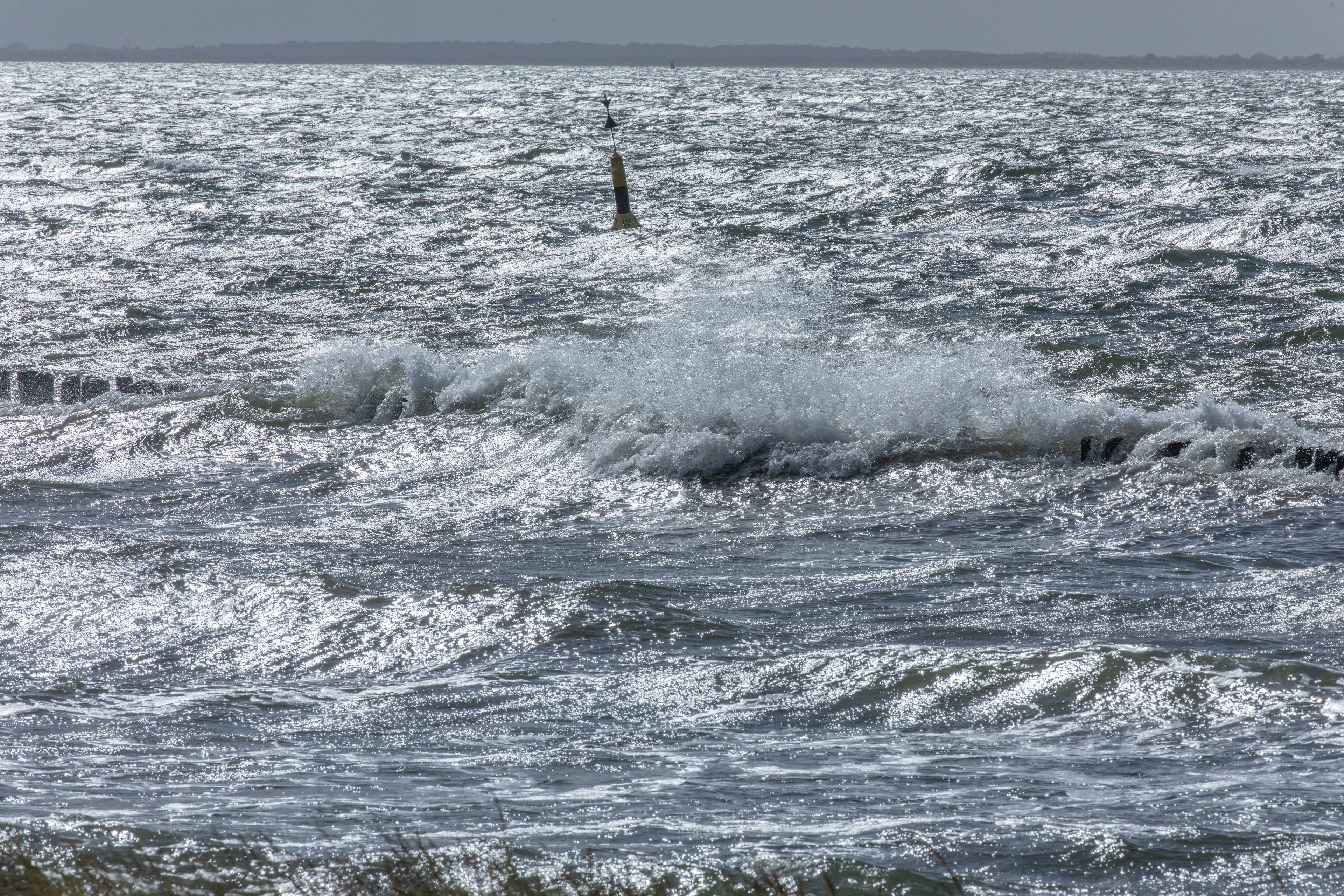 A body of water with waves and a buoy.