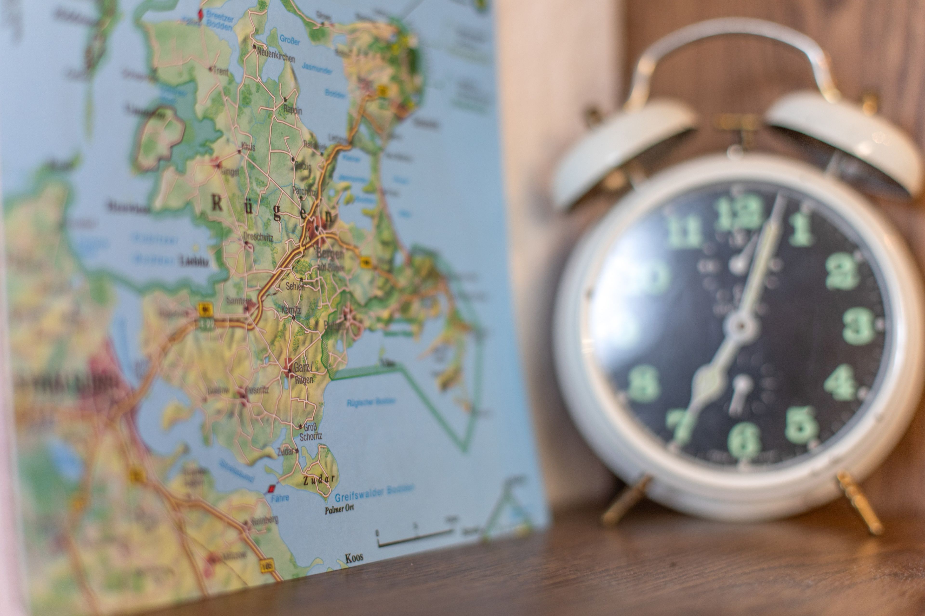 A map and an alarm clock on a wooden surface.
