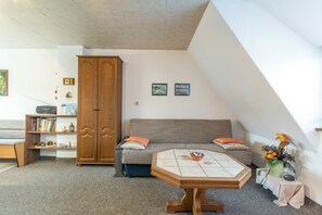 A cozy living room with a sofa, a wooden cabinet, a small table, and a bookshelf.