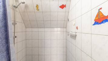 A tiled shower area with a showerhead, a towel rack, and decorative fish tiles on the wall.