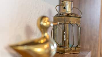 A brass lantern and a brass bird-shaped object on a wooden shelf.