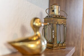 Une lanterne en laiton et un objet en laiton en forme d’oiseau, posés sur une étagère en bois.