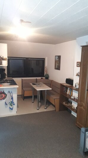 Een compacte leefruimte met een kitchenette, een eethoek en een zithoek.
