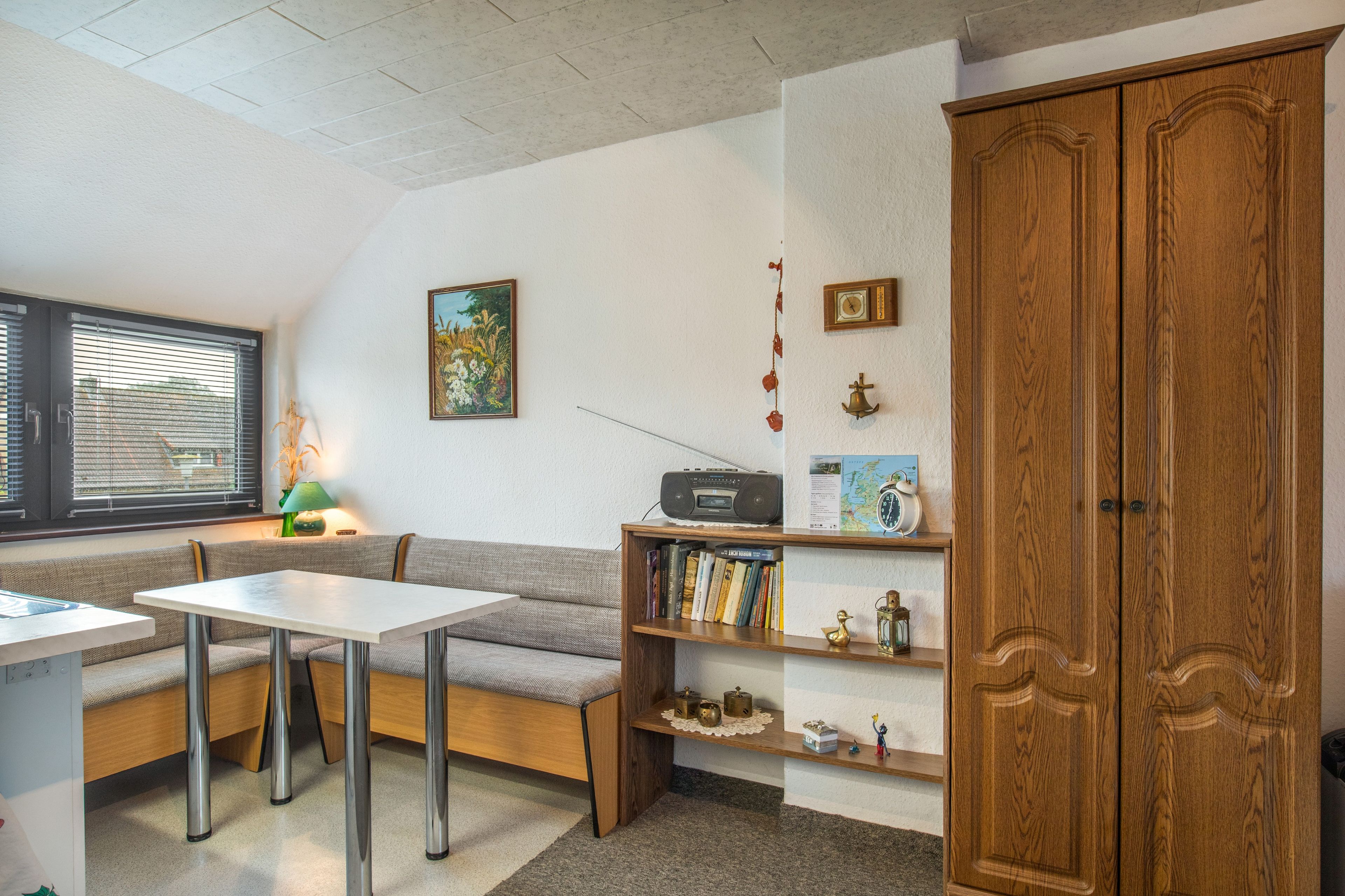 A cozy room with a wooden cabinet, a table, a bench, and a bookshelf.