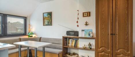 A cozy room with a wooden cabinet, a table, a bench, and a bookshelf.