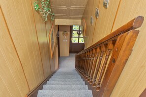 Un escalier en bois, doté d’une rampe, mène à une porte avec une fenêtre.
