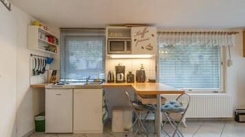 A compact kitchen with a built-in microwave, a coffee maker, and a kettle on the counter.