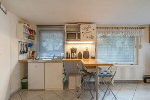 Una cocina compacta con microondas integrado, cafetera y hervidor sobre la encimera.