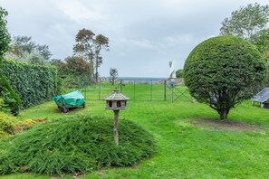 A garden with a bird feeder, a wheelbarrow, and a solar panel.